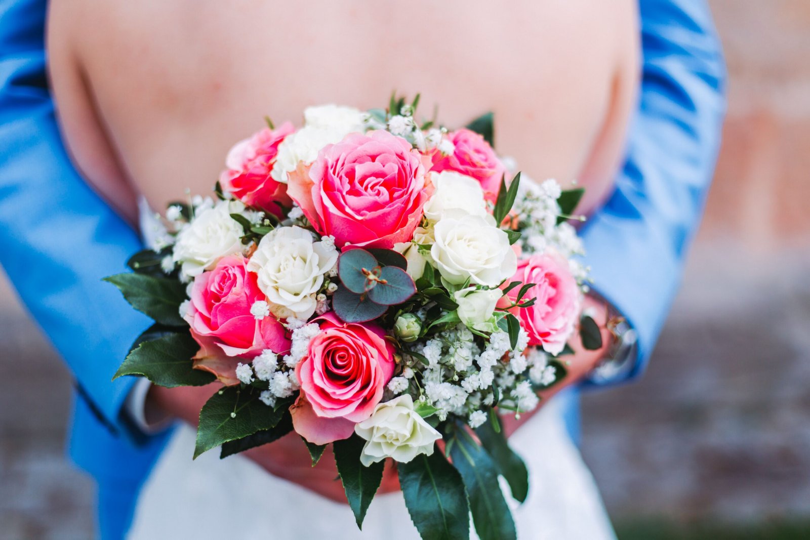 Groom holding a colorful bouquet while embracing his bride