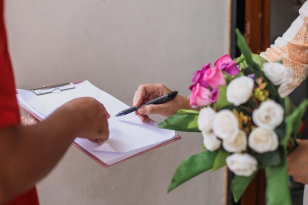Client signing a wedding vendor agreement with flowers on the table